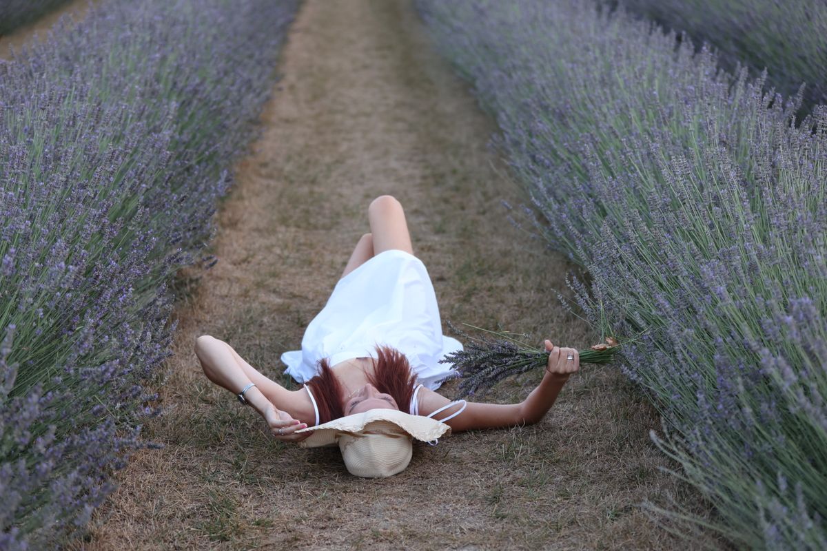 Femme allongée dans un champ de lavande, symbole de détente et de sommeil apaisé