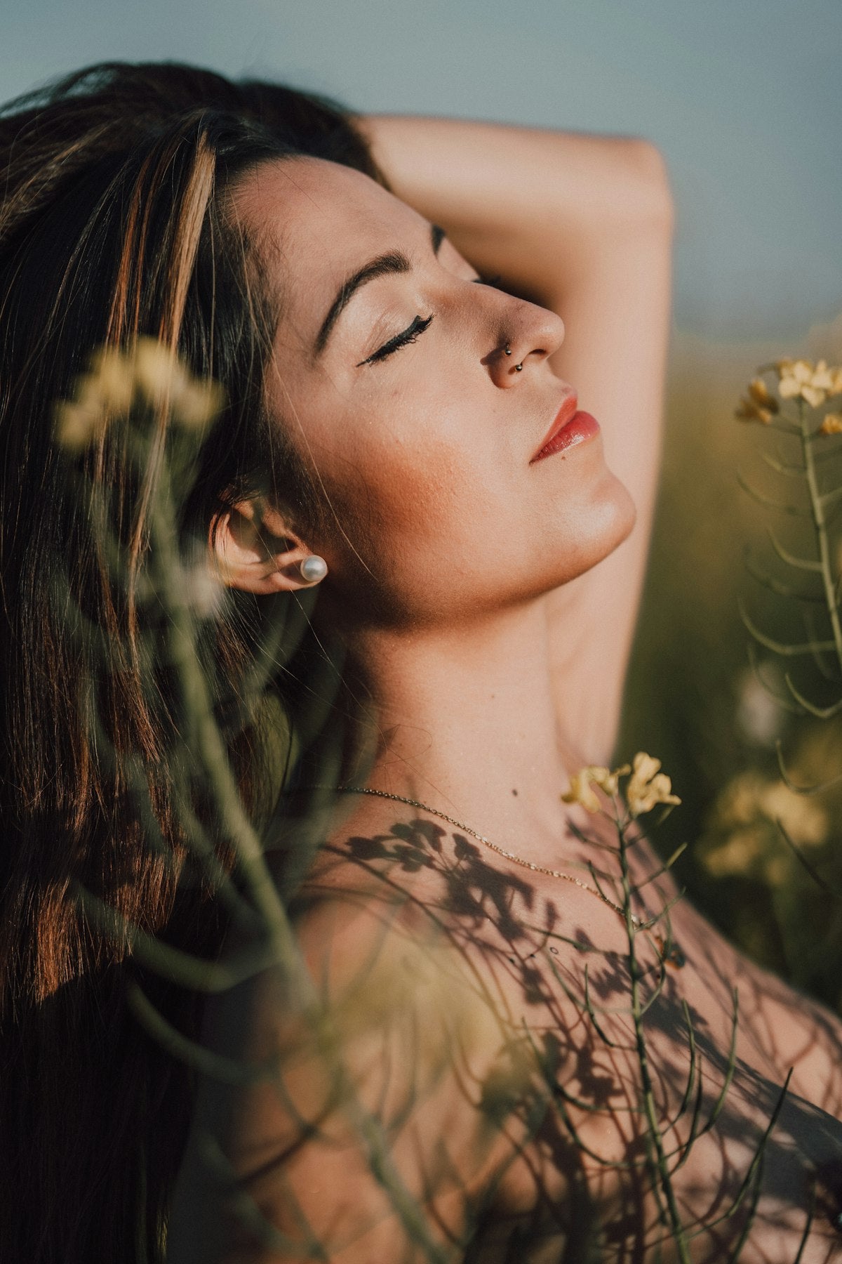 Femme sereine les yeux fermés dans un champ de fleurs - gestion du stress et du cortisol