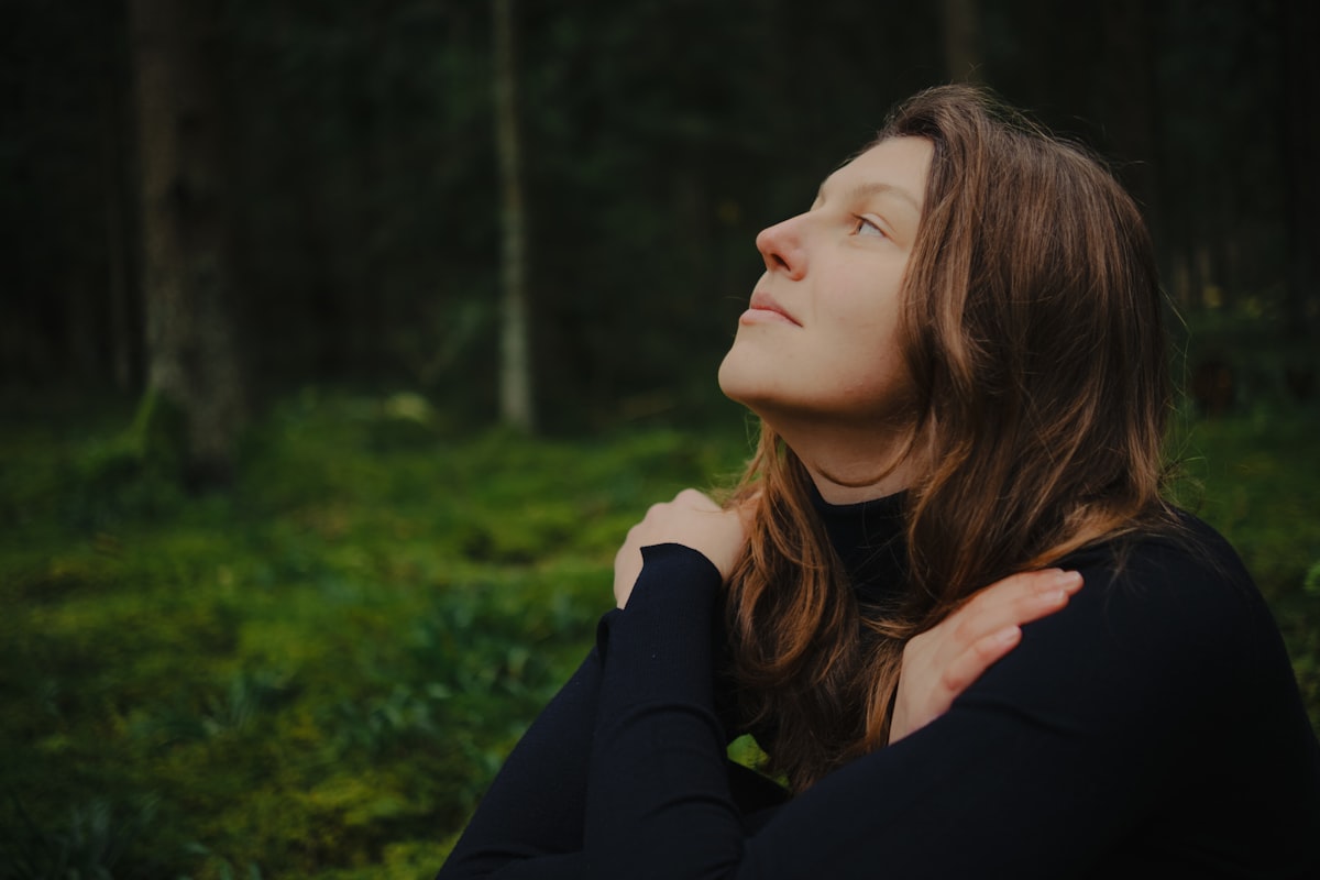 Femme sereine dans la forêt, yeux fermés, gestion du stress et du cortisol